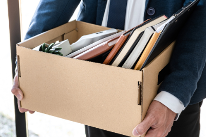 Worker leaving office with box of belongings after being fired due to workplace injury, with termination letter highlighted
