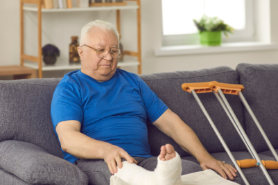 Worker with a cast sitting at home, recovering from a workplace injury and waiting for workers' compensation benefits