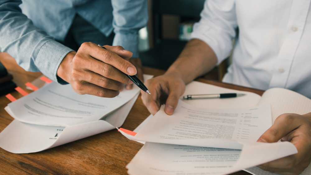 Review the QME Report 2 ppl reviewing paperwork worker's comp employer doctor dilemmas